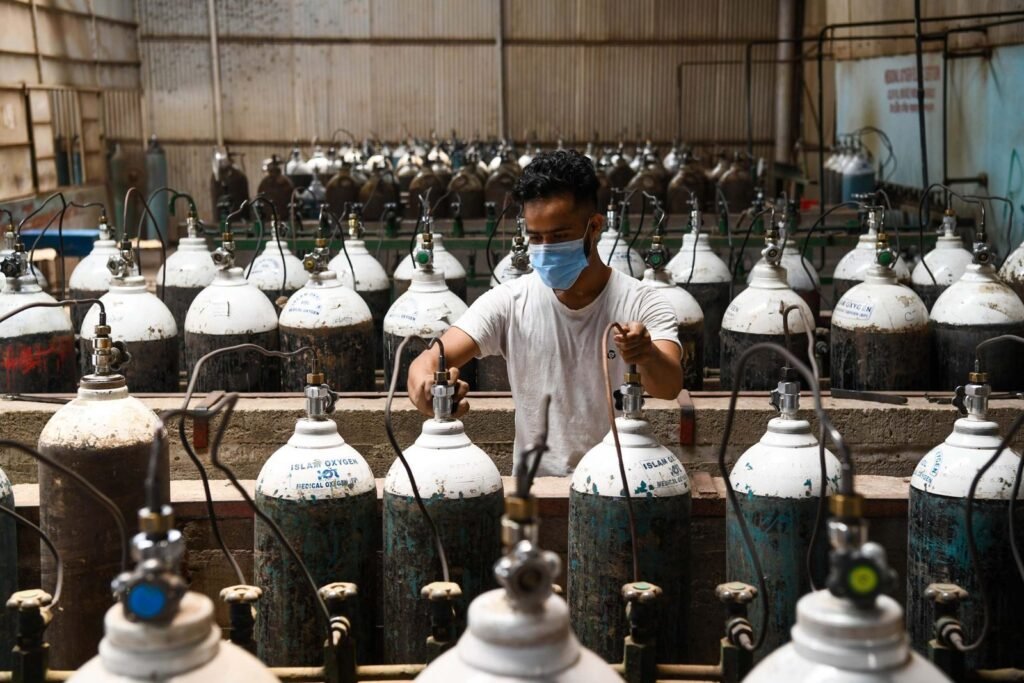 A worker refilling oxygen cylinders at an oxygen plant.