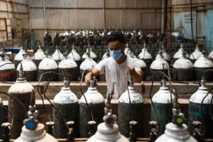 A worker refilling oxygen cylinders at an oxygen plant.
